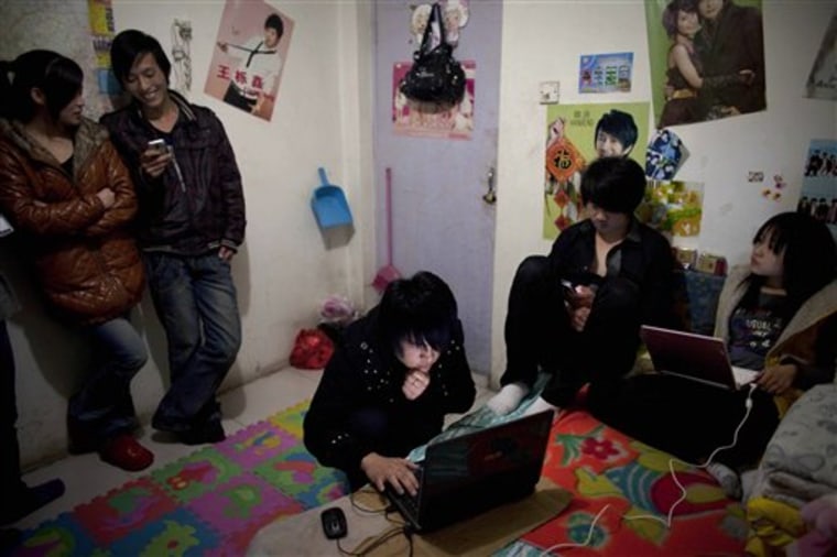 In this April 1, 2010 photo, Shang Meirong, 21, right, and her friends gather in her rented room to play computer games and socialize at Tang Jialing village where young educated Chinese crowd in shared rooms in Beijing, China. Rising living costs and low salaries have forced China's millions of post-80s graduates, dubbed the \"ant generation,\" to crowd together in slums in China's largest cities. (AP Photo/Alexander F. Yuan)